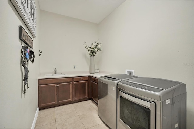 laundry area featuring cabinets, washer and clothes dryer, sink, and light tile patterned floors