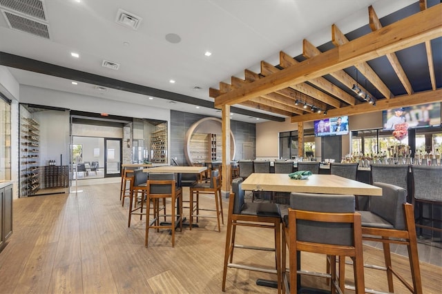 dining space with light hardwood / wood-style flooring and beamed ceiling