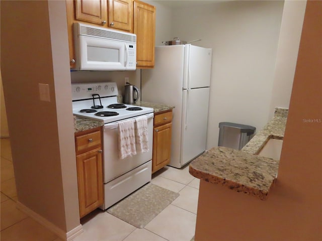 kitchen featuring light tile patterned flooring, white appliances, and sink