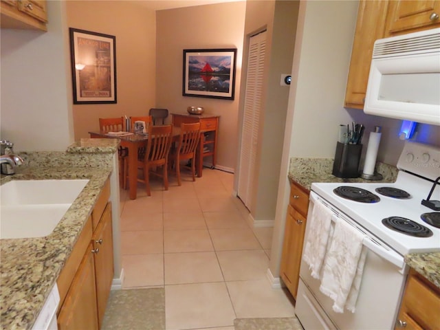 kitchen featuring light stone counters, sink, white appliances, and light tile patterned floors