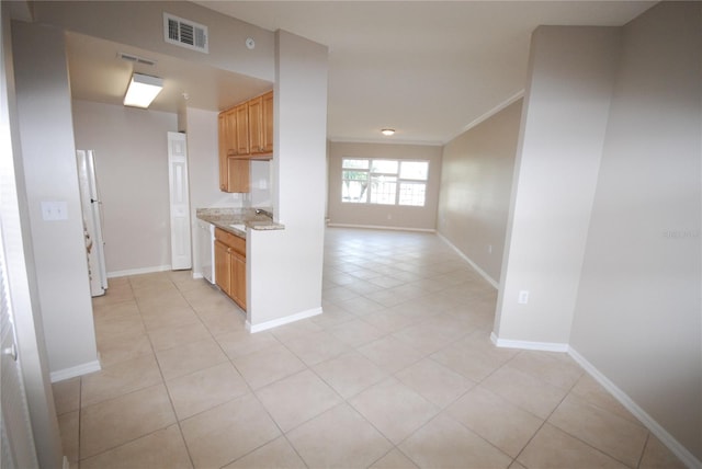 kitchen featuring light tile patterned floors, crown molding, and light stone countertops