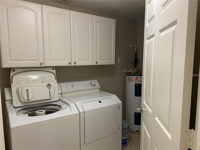 clothes washing area featuring cabinets, electric water heater, a textured ceiling, and washer and clothes dryer