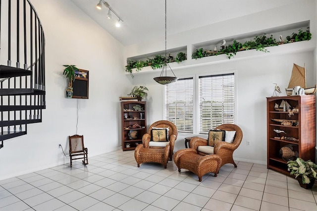 living area with track lighting, lofted ceiling, and light tile patterned floors