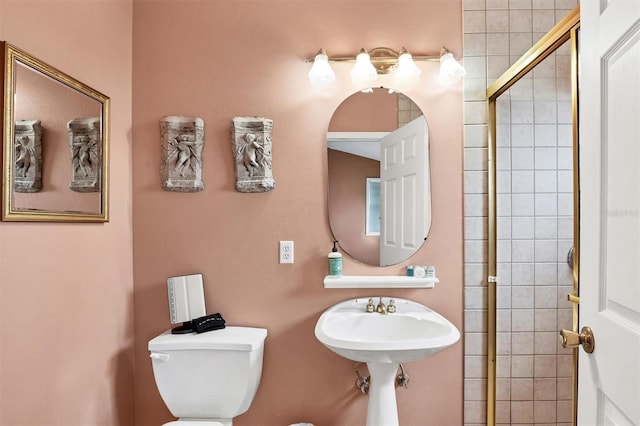 bathroom with sink, a shower with shower door, and toilet