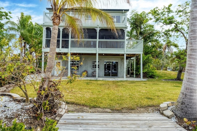 rear view of property featuring a lawn, a sunroom, and a patio