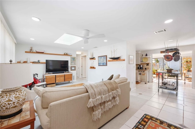 living room featuring light tile patterned floors, a skylight, and ceiling fan