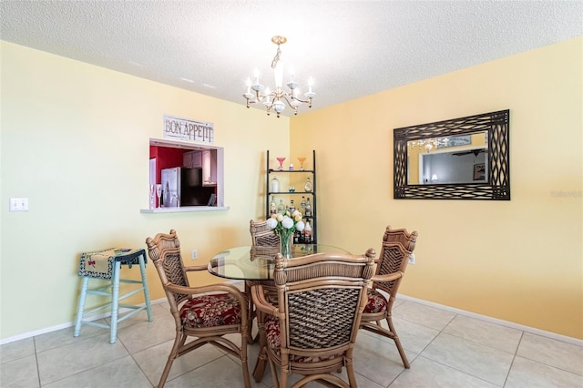 tiled dining room with a textured ceiling and a chandelier