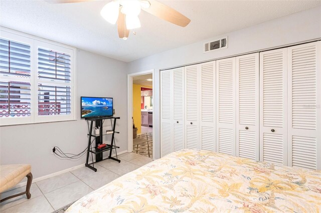 bedroom with ceiling fan, a closet, and light tile patterned floors