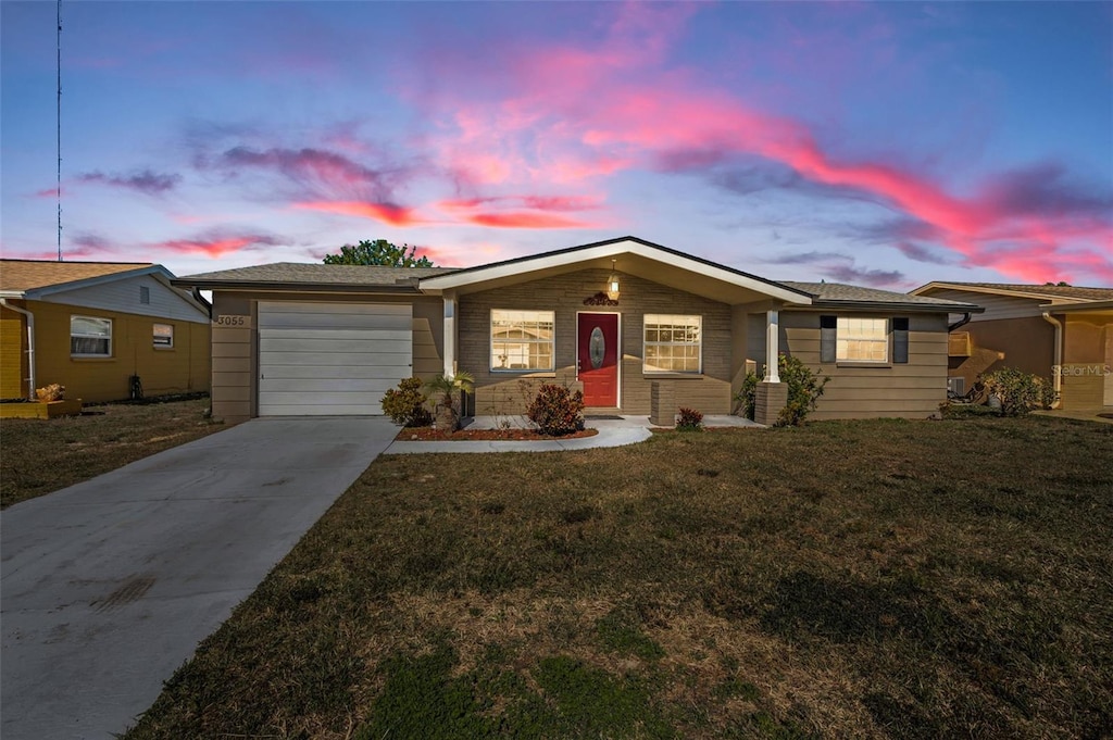 ranch-style house with a garage and a yard