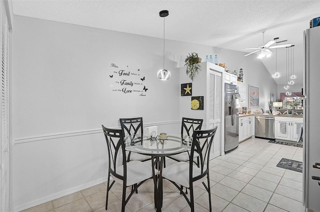 tiled dining space with lofted ceiling, a textured ceiling, and ceiling fan