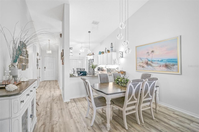 dining area featuring high vaulted ceiling, ceiling fan, and light wood-type flooring