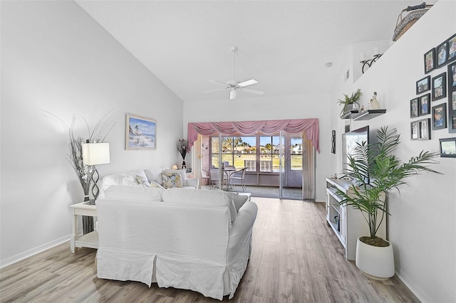 living room with ceiling fan, high vaulted ceiling, and light hardwood / wood-style floors