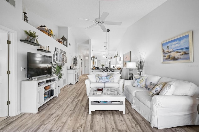 living room with ceiling fan, high vaulted ceiling, light hardwood / wood-style floors, and a textured ceiling