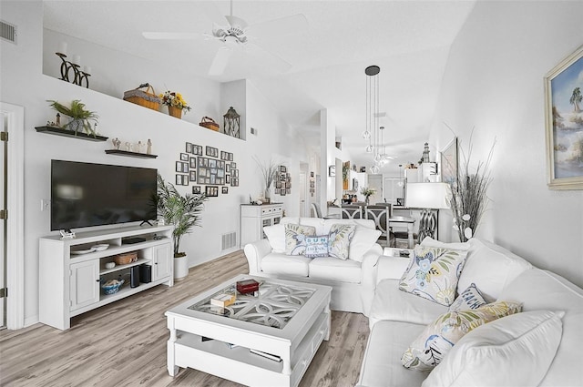 living room with high vaulted ceiling, ceiling fan, and light hardwood / wood-style flooring