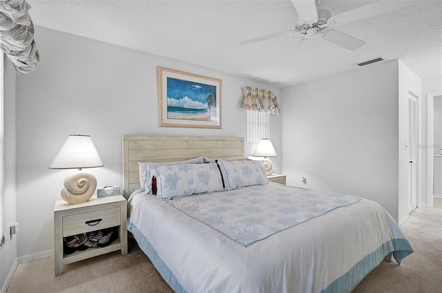 carpeted bedroom with ceiling fan, a closet, and a textured ceiling