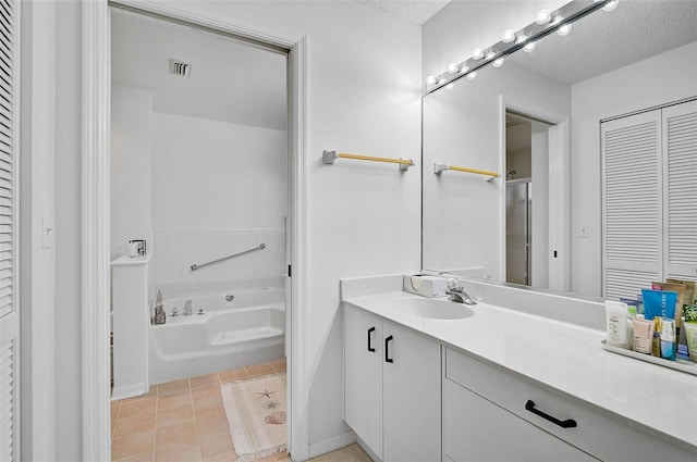 bathroom featuring tile patterned flooring, vanity, a textured ceiling, and a tub to relax in