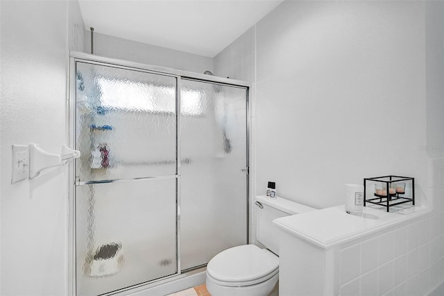 bathroom with a shower with shower door and toilet