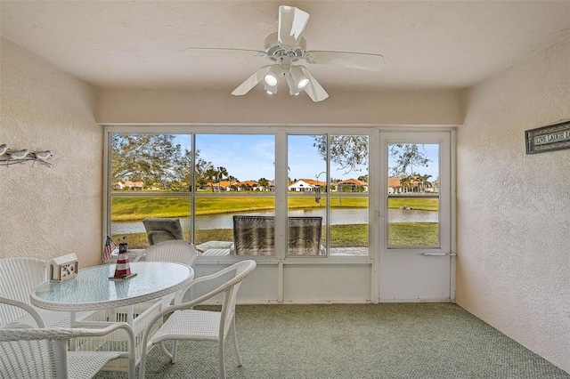 sunroom with a water view and ceiling fan