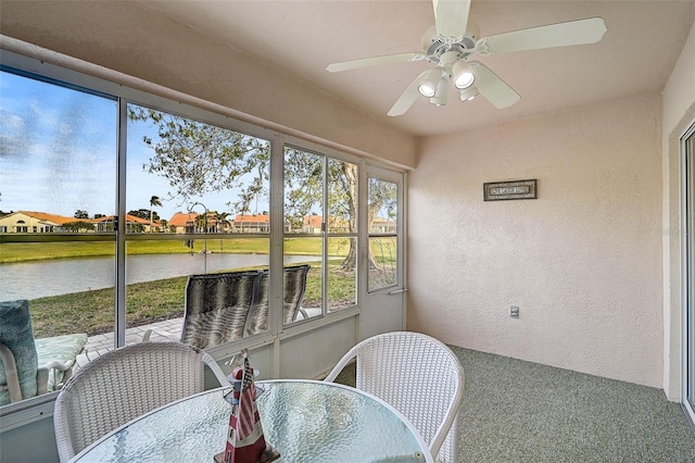 sunroom / solarium with ceiling fan and a water view