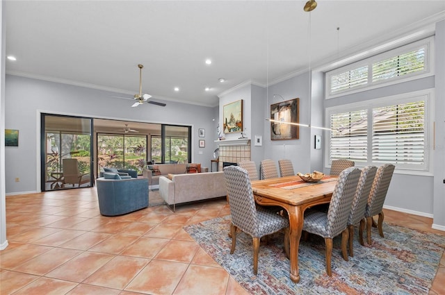 dining space with light tile patterned flooring, crown molding, ceiling fan, and a fireplace