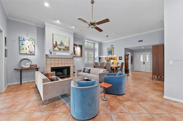 living room featuring ceiling fan, ornamental molding, a fireplace, and light tile patterned floors