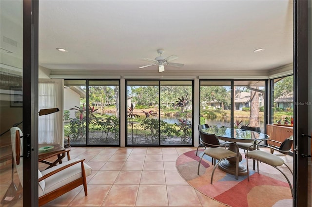 sunroom with ceiling fan and a water view