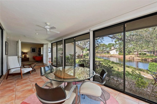 sunroom / solarium with a water view and ceiling fan