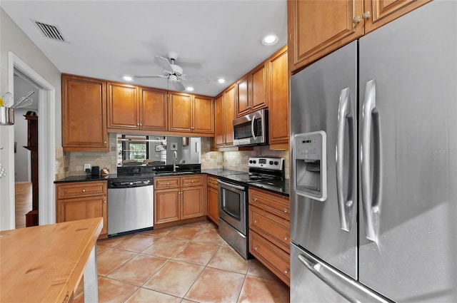 kitchen with appliances with stainless steel finishes, sink, light tile patterned floors, and backsplash