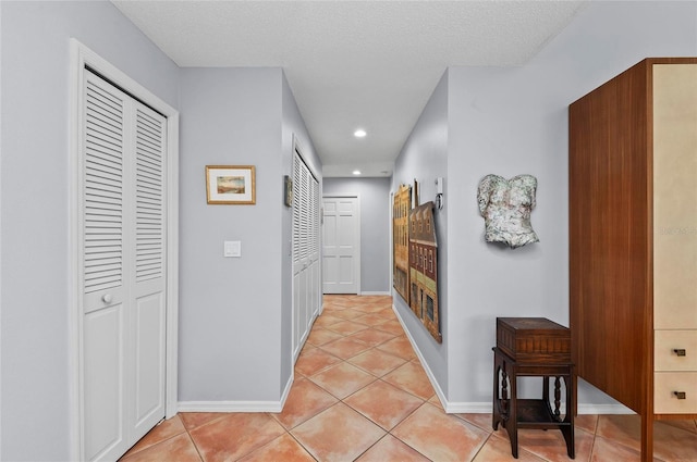 hallway with a textured ceiling and light tile patterned floors