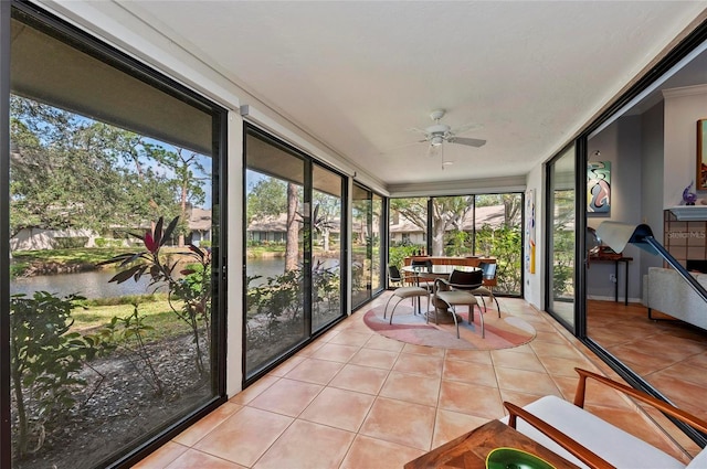 sunroom / solarium featuring a water view and ceiling fan