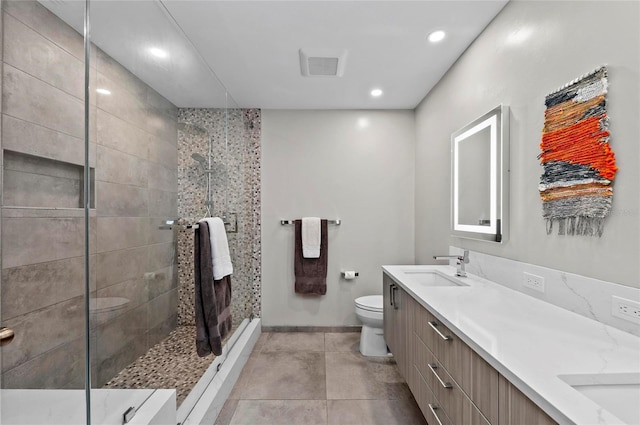 bathroom featuring tiled shower, vanity, toilet, and tile patterned flooring