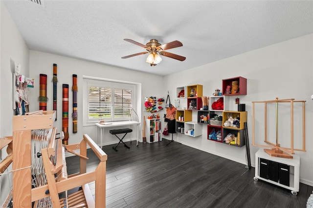 rec room featuring ceiling fan, dark hardwood / wood-style flooring, and a textured ceiling