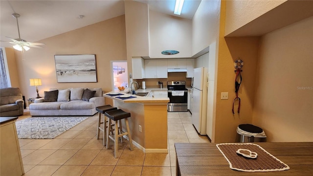 kitchen featuring stainless steel electric range oven, sink, a kitchen breakfast bar, white refrigerator, and kitchen peninsula