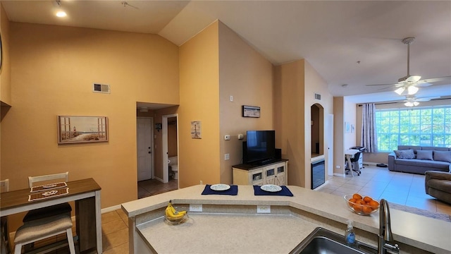 kitchen with ceiling fan, high vaulted ceiling, sink, and light tile patterned floors