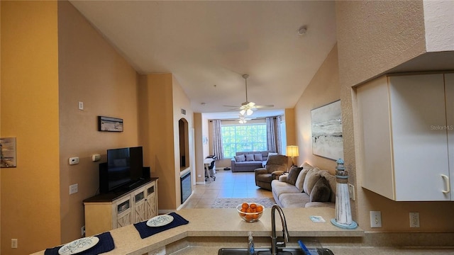 living room with lofted ceiling, sink, light tile patterned floors, and ceiling fan