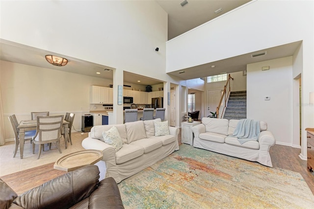 living room featuring a towering ceiling and light hardwood / wood-style floors