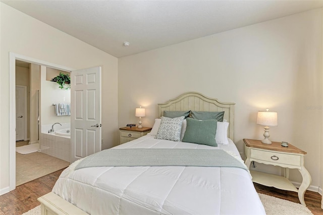 bedroom featuring connected bathroom, hardwood / wood-style floors, and lofted ceiling