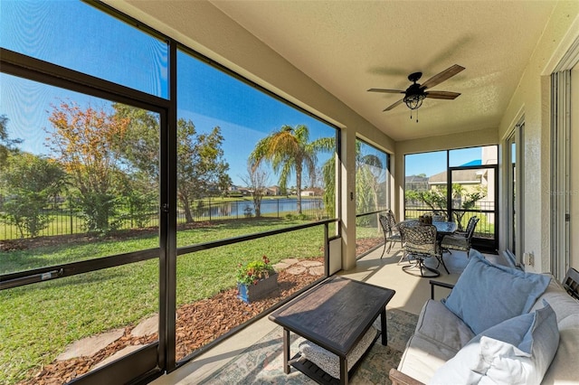 sunroom / solarium with ceiling fan and a water view