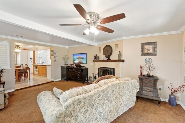 living room with a tile fireplace, carpet flooring, ceiling fan, and crown molding