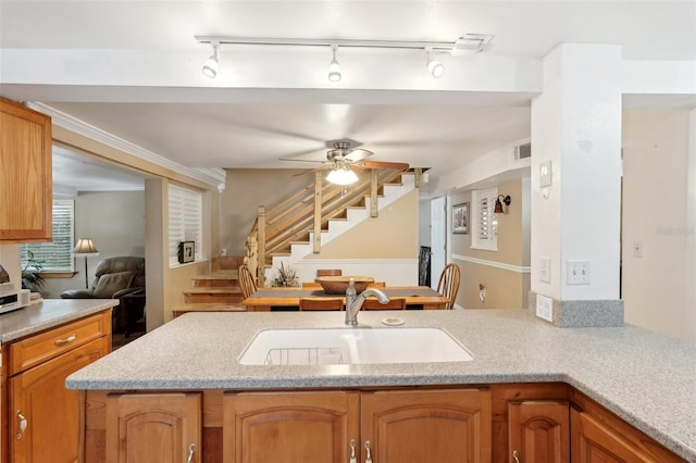 kitchen featuring light stone counters, ceiling fan, kitchen peninsula, and sink