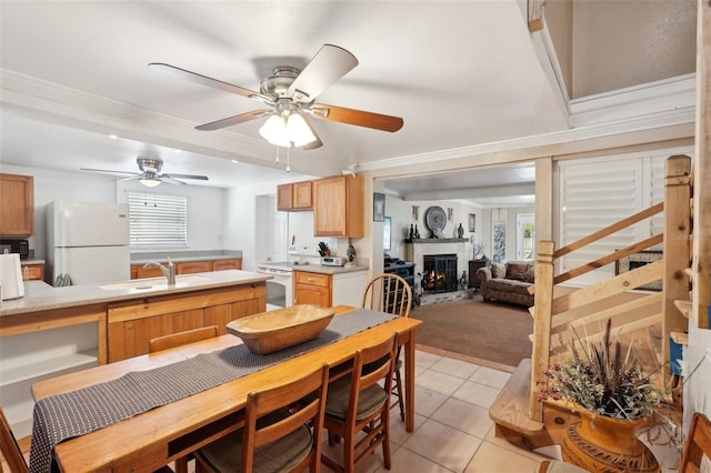 dining area featuring light tile patterned floors, crown molding, sink, and ceiling fan