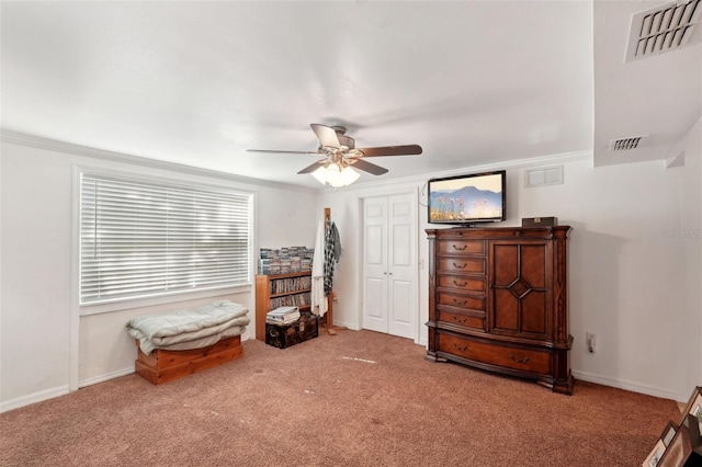 interior space with ceiling fan, ornamental molding, and carpet