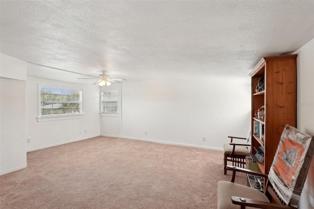 unfurnished room featuring a textured ceiling, light colored carpet, and ceiling fan