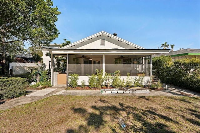 back of house with a sunroom and a lawn