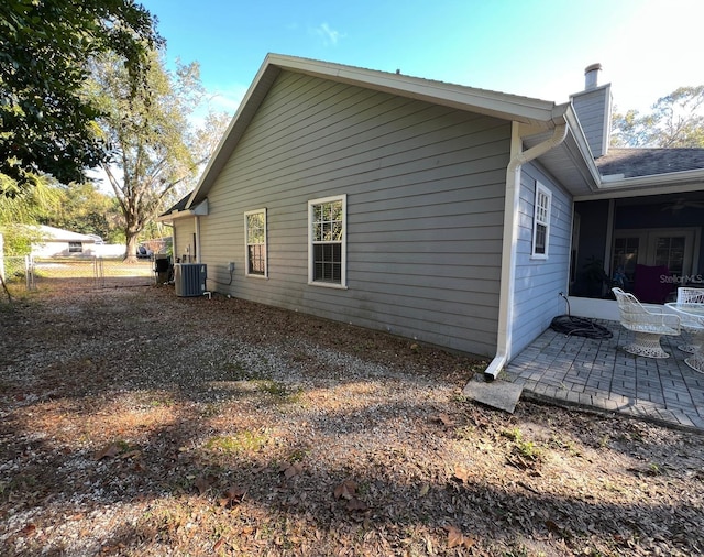 view of side of home with central AC unit and a patio area