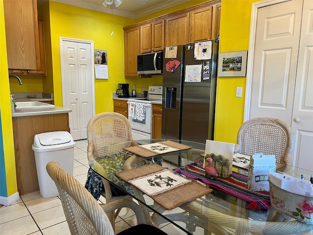 kitchen with sink, crown molding, light tile patterned flooring, and appliances with stainless steel finishes