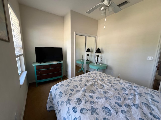 bedroom with ceiling fan, dark carpet, and a closet