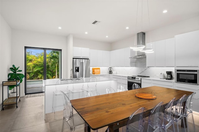 kitchen featuring exhaust hood, a center island, hanging light fixtures, stainless steel appliances, and white cabinets