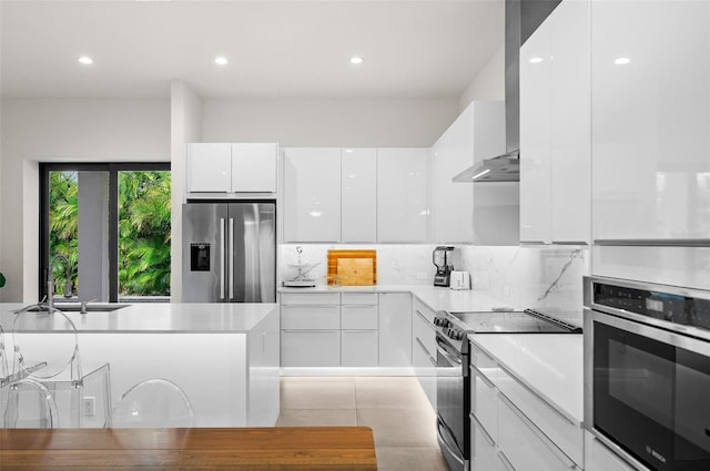 kitchen with extractor fan, appliances with stainless steel finishes, white cabinets, and backsplash