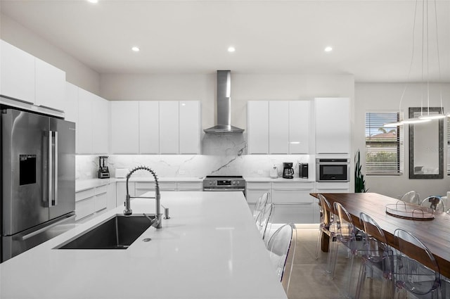 kitchen featuring stainless steel appliances, sink, white cabinets, and wall chimney exhaust hood